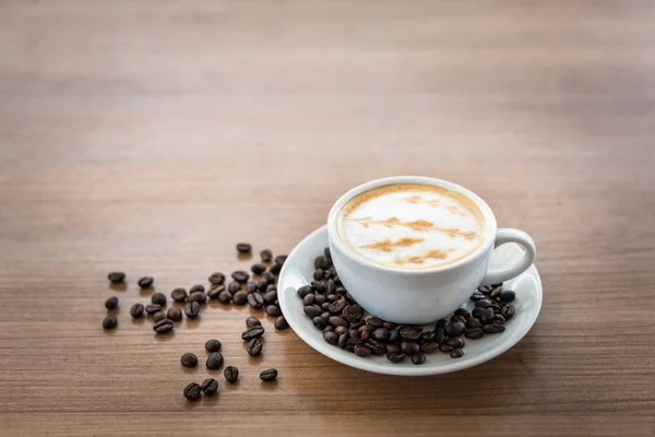 Sıcak kahve ile sanat desen ahşap masa arka plan üzerinde beyaz Kupası 