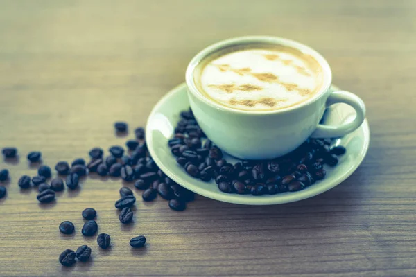 Sıcak kahve ile sanat desen ahşap masa arka plan üzerinde beyaz Kupası 