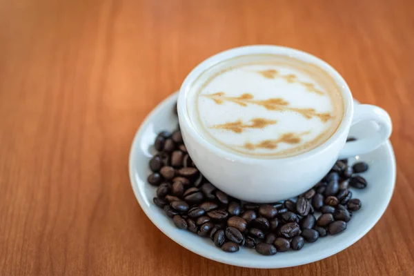 Sıcak kahve ile sanat desen ahşap masa arka plan üzerinde beyaz Kupası 