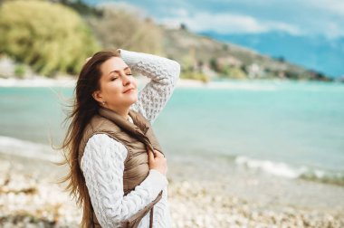 Lake Geneva, İsviçre tarafından güzel bahar günü zevk mutlu kadın. Kahverengi yastıklı ceket ve beyaz kazak giyen kız moda