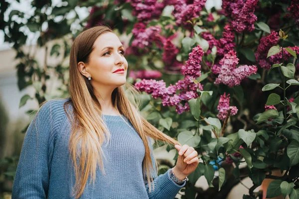 スプリング ライラック ガーデンでポーズ サイズのプルオーバーの上青身に着けている若い美しい女性像 — ストック写真