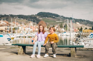 İki komik çocuğu, küçük kardeşi ve kız birlikte küçük Lutry bankta oturan gölün dışında oynarken port, Lausanne alan, İsviçre