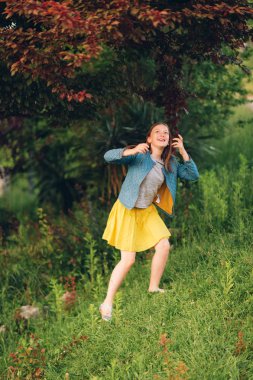 Genç bir ağaç günbatımı ışıkta güzel bahçede oynayan kız çocuk