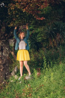 Genç bir ağaç günbatımı ışıkta güzel bahçede oynayan kız çocuk