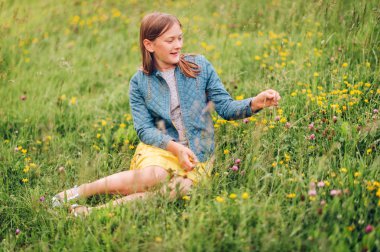 Sevimli küçük kız yaz bahçede oynarken denim ceket giyiyor 