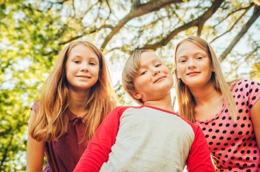 Grup birlikte güneşli bir günde dışarıda oynayan 3 komik çocuk. İki kız ve küçük çocuk parkta eğleniyor