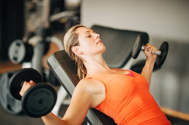 Genç kadın dumbells beden eğitimi dersinde, sağlıklı spor hayatı ile çalışma dışarı yerleştirmek