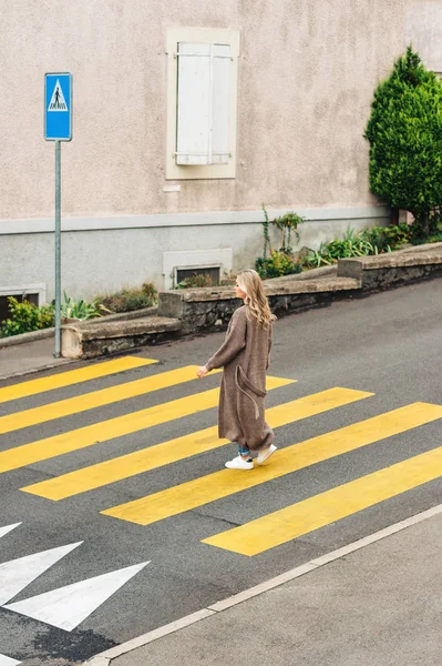 穿着长针织羊毛衫的时尚女子横穿马路 — 图库照片