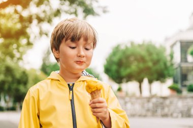 Mango dondurma yeme sarı yağmur ceket giyen sevimli küçük çocuk