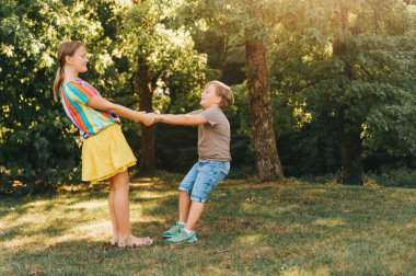 Grup iki çocuk birlikte yaz parkta oynarken etrafında dönen birlikte elele