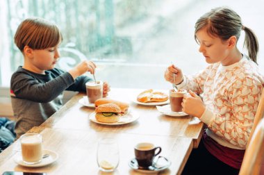 İki komik çocuğu kafede yağmurlu bir günde sıcak çikolata içme