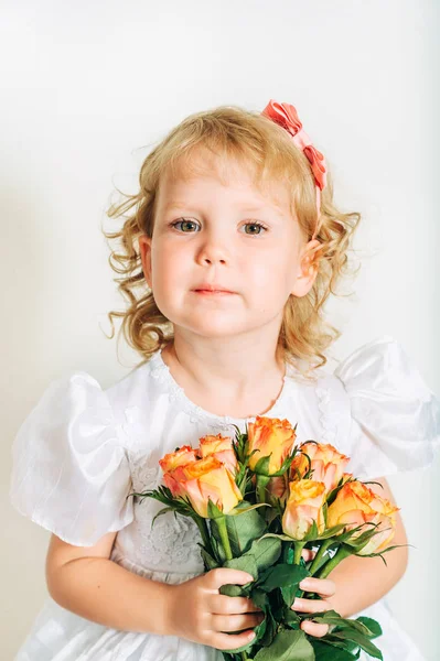 スタジオ撮影機会に白を着てかわいい 歳の幼児の女の子のドレス 黄色オレンジ色のバラの花束を持って — ストック写真