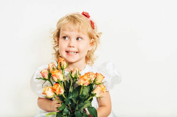 スタジオ撮影機会に白を着てかわいい 歳の幼児の女の子のドレス 黄色オレンジ色のバラの花束を持って — ストック写真