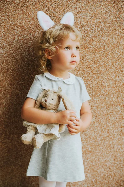 ソフト バニー グッズを持ってウサギの耳を身に着けている愛らしい幼児女の子の肖像画 — ストック写真