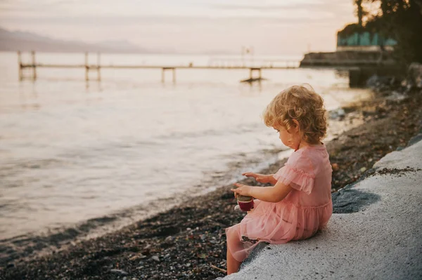 可爱的幼儿女孩休息在湖边的一个温暖的夜晚 拿出鹅卵石从她的鞋 — 图库照片