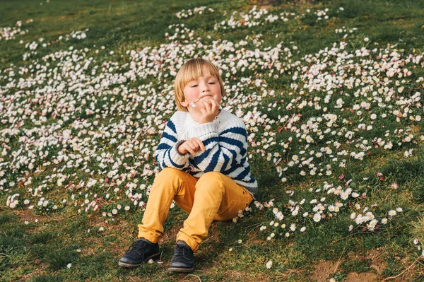 春の愛らしい男の子のデイジーの花でいっぱい草で休んでストライプ マリン プルオーバー 黄色茅野ズボンを身に着けている肖像画 — ストック写真