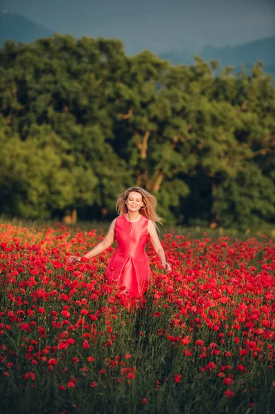 Beautiful woman enjoying nice day in poppy field, wearing pink dress