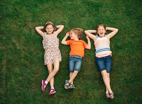 屋外楽しい幸せな様子 夏の公園で遊ぶ子供たち 小さな男の子と緑の新鮮な草の上に横たわる二人の女の子 — ストック写真