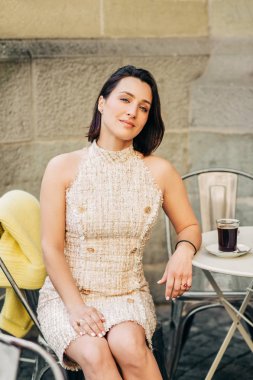 Güzel şık kadın kahve fincan ile sokak kafede dinlenme, şık elbise giyiyor