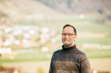 Kahverengi pullover ve gözlük giyen 50 yaşındaki adamın dış portre