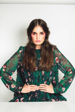 Uzun koyu saçlı, parlak pembe makyaj, yeşil elbise giyen, bel ellerini tutmak ile güzel kadın Stüdyo çekim