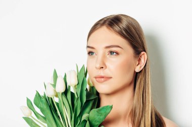 Beyaz taze lale buketi tutan, sarı saçlı ve çıplak makyaj ile güzel genç kadının yakın portresi