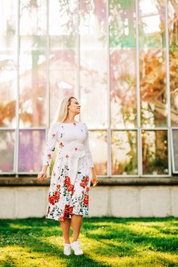 Mutlu kadın güneşli parkta güzel bir gün zevk, kırmızı güller ile beyaz elbise giyiyor 