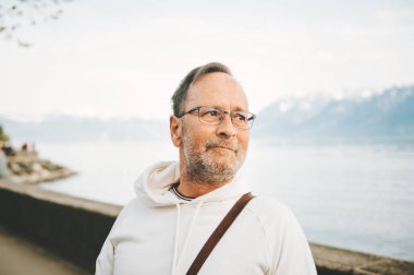 Dağlarla güzel göle hayran olan yakışıklı adamın portresi, beyaz kazak giyme