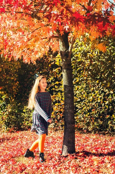 非常に晴れた日に木の下で葉で遊ぶ小さな女の子 — ストック写真