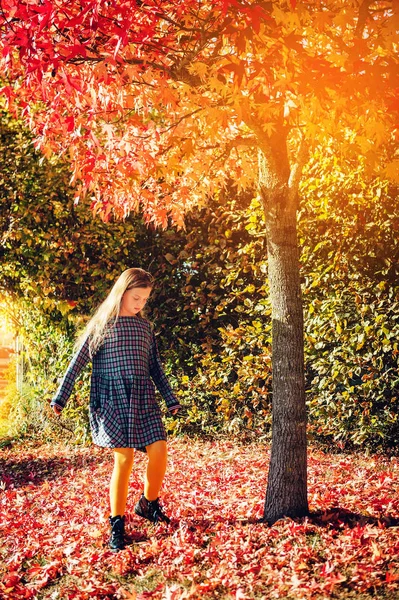 非常に晴れた日に木の下で葉で遊ぶ小さな女の子 — ストック写真