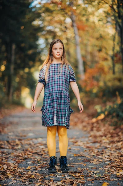 かわいい若い女の子の秋の肖像画 森の中で屋外でポーズをとる子供モデル チェック柄のドレスと黄色のタイツを着て — ストック写真