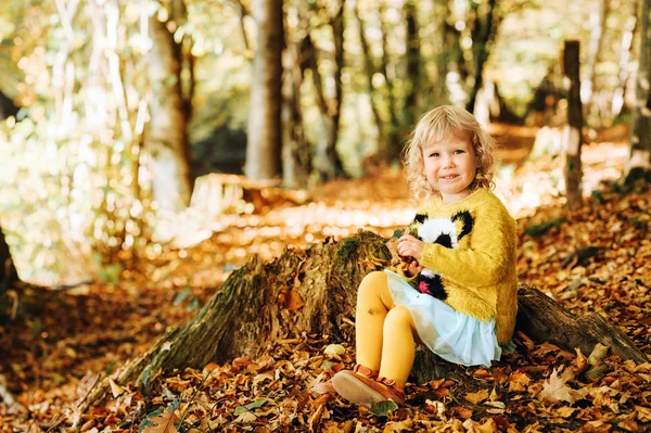 非常に晴れた日に秋の森で葉で遊ぶ小さな幼児の女の子 — ストック写真