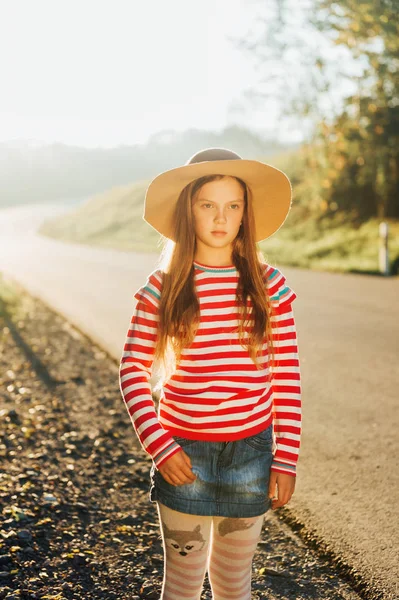 大きな帽子 ピンクのストライププルオーバーとデニムスカートを着てかわいい女の子の屋外の肖像画 — ストック写真