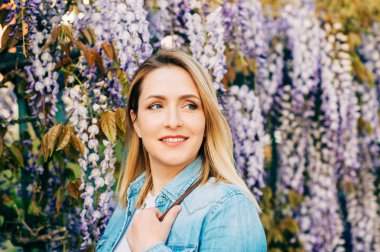 Wisteria bahçede dışarıda poz denim gömlek giyen zarif genç kadının Bahar yakın portresi