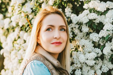 Çiçek bahçesinde dışarıda poz veren güzel genç kadının bahar yakın portresi