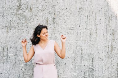 Gri duvar arka planda poz güzel genç kadının Kentsel moda portre, kollar kadar
