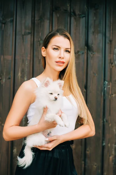 白いポメラニアンスピッツ子犬を持つ幸せな若い女性の屋外の肖像画 — ストック写真