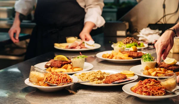 Food orders on the kitchen table in the restaurant, pasta spaghetti with tomato sauce and cheese, schnitzel with spaetzle