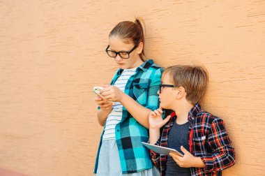 Komik çocuklar tablet pc ile oynarken açık havada. Elektronik aletler kullanan küçük çocuklar