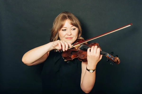 Studio portrait of beautiful woman with violin, black background