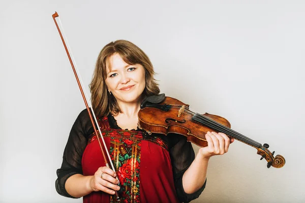 Studio portrait of beautiful woman with violin, white background