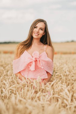 Buğday tarlasında poz veren mutlu genç kadının yaz portresi