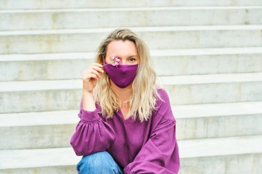 Mor bluz ve maske giyen güzel bir kadının açık hava moda portresi.
