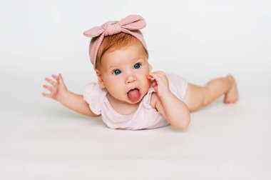 Sevimli kızıl saçlı bebeğin portresi. Beyaz arka plan, pembe vücut ve saç bandı takıyor.