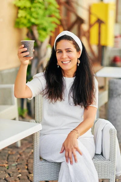 Güzel orta yaşlı İspanyol kadın sabah kahvesini terasta içiyor.