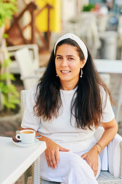 Güzel orta yaşlı İspanyol kadın sabah kahvesini terasta içiyor.