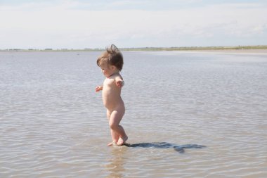 Running little girl among the lake at summer. Salt shallow lake in Russia. Loneliness  concept in big world clipart