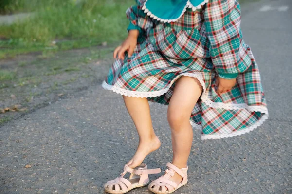 Little girl legs wearing open-toe sandals at summer. Child in green dress