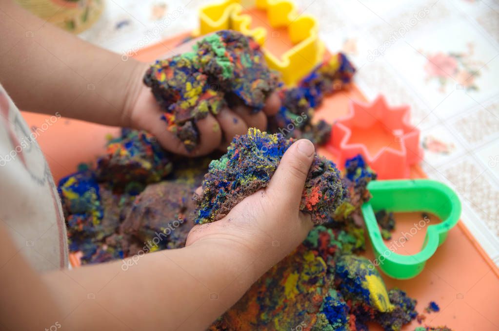 Child hands playing multicolored kinetic sand. children activity game toy for model forming craft and sculpture art. kids education  technology