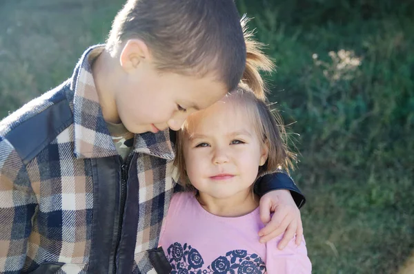 男孩和小女孩拥抱肖像 阳光明媚的孩子在户外愉快地微笑 友谊兄弟姐妹 兄弟拥抱小妹妹 — 图库照片